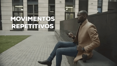 Homem cruzando as pernas enquanto segura o seu celular.